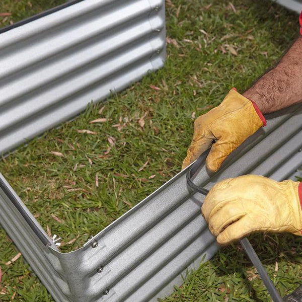 What should be placed at the bottom of a raised metal garden bed?